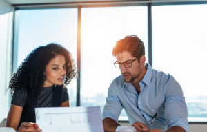 increase your ROI with landlord-tenant software header image: woman and man in their 30s looking at a document together with the sun shining in the office window