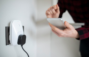 smart amenities header image: smart plug in outlet with hands holding a smartphone next to it