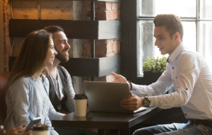 auto-tenant screening image: man talking to tenant couple in front of computer