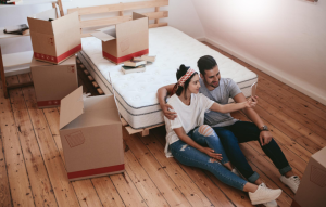 tenant communication header image: young couple sitting on floor of room next to moving boxes videochatting on the phone