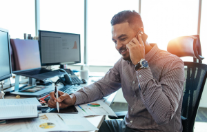 online rent collection header image: man talking on phone at computer desk with papers