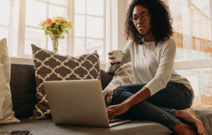 employment references for tenants image: woman drinking coffee and sitting on couch working on laptop