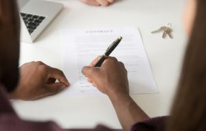 how to do a background check image: man's hands holding a pen and signing a contract