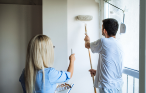 woman hold paint samples gesturing toward man painting the wall for a rental inspection checklist