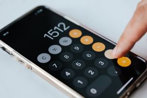 401k vs roth ira: finger typing numbers in on the calculator app of a phone