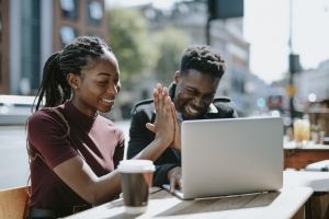 best states to buy rental property hero image of young couple high fiving each other in front of laptop