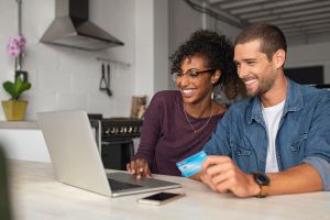 hero image for rentredi vs quickbooks payments: image of a young couple smiling happily at their laptop holding a credit card