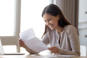 free landlord reference letter template hero image: smiling woman holding a piece of paper & excited