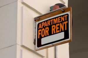 tenants scamming landlords hero image: apartment for rent sign on side of building