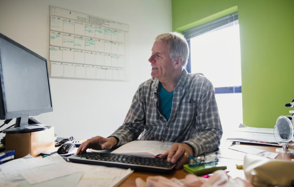 fill vacant units image: picture of a 60-year old man in a flannel shirt working on the computer sitting at his desk