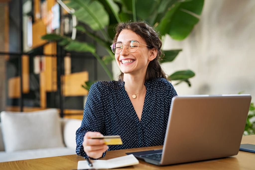 smiling woman holding credit card for property management collection payment on laptop