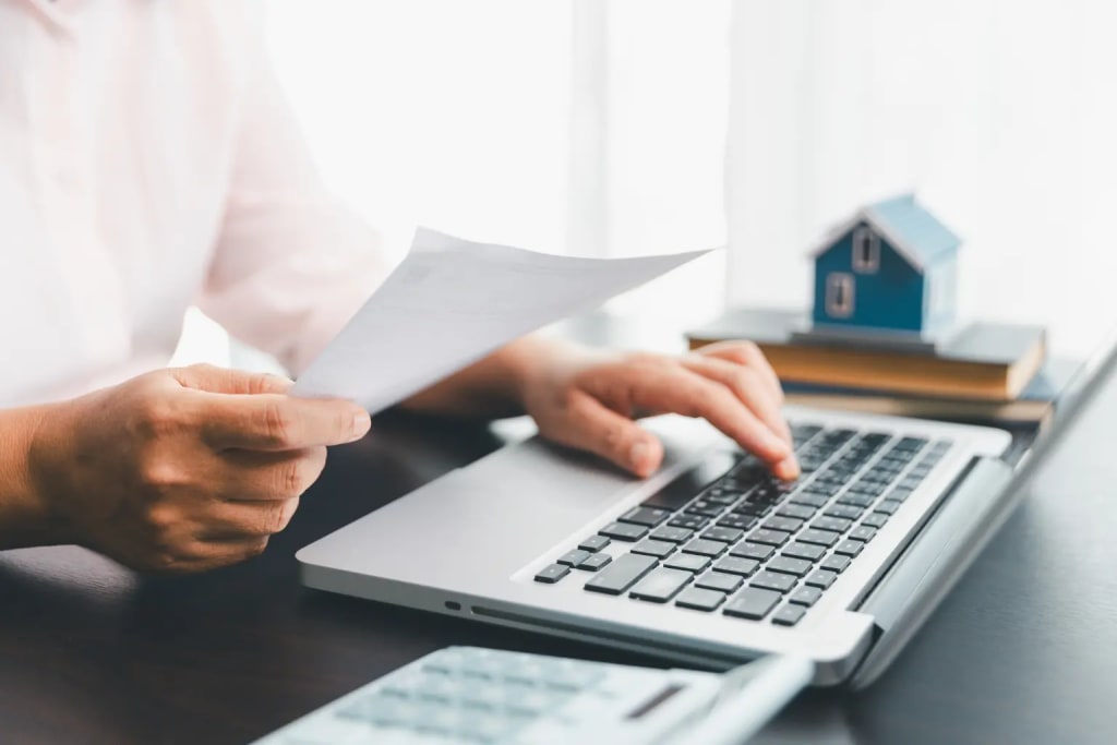 Rental compliance software for landlords shown with a person reviewing property documents while working on a laptop.