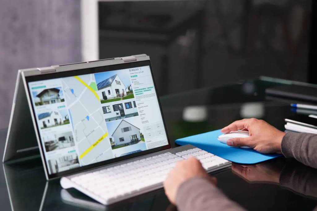 Property management computer software showing property listings and map view on a touchscreen laptop.