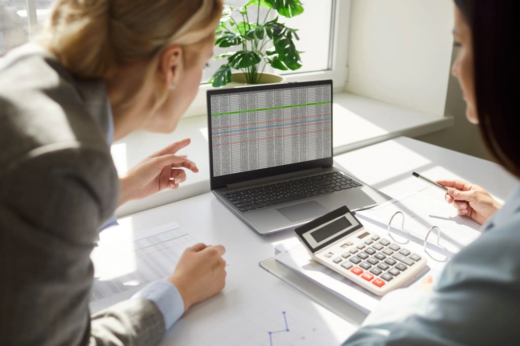 Accounting Tools Every Property Management Company Needs shown by team reviewing financial spreadsheet on laptop with calculator.