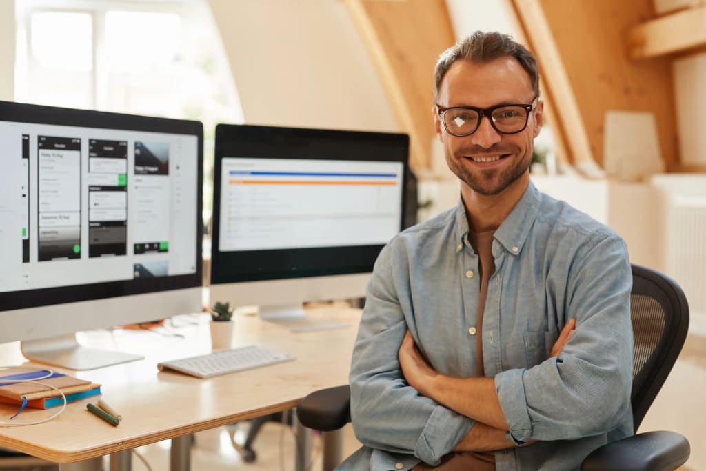 Property management and accounting software displayed on dual monitors in a modern office workspace.