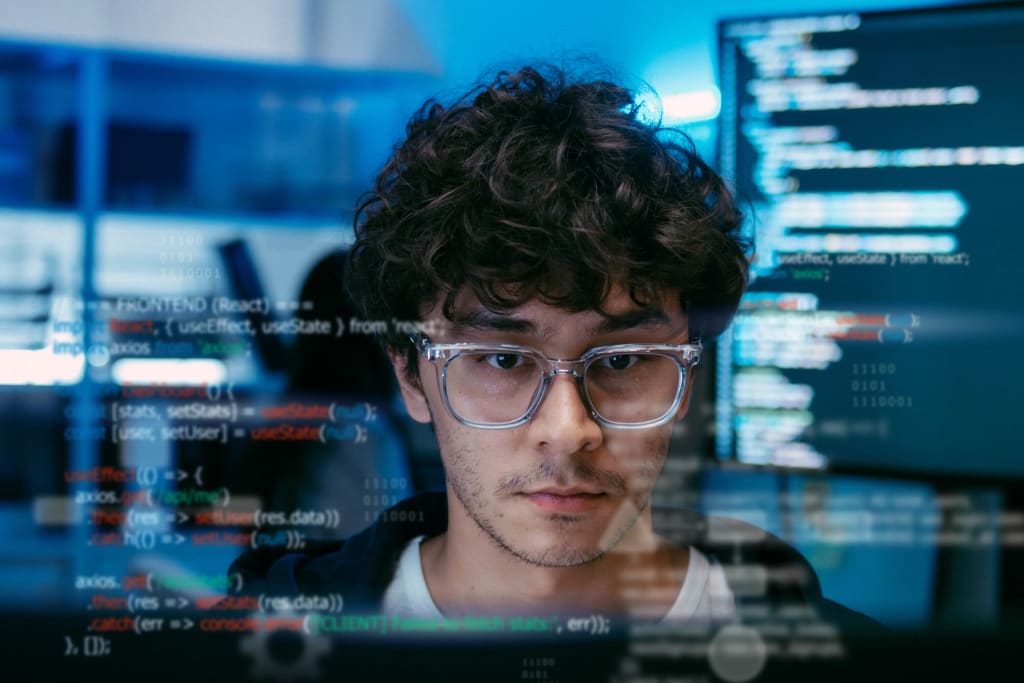developer focused on building preventive maintenance tracking software surrounded by code on screens