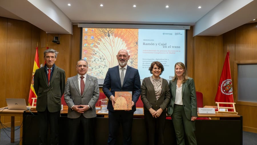 A group of five individuals stand in a formal setting, holding a book related to the presentation of Cajal