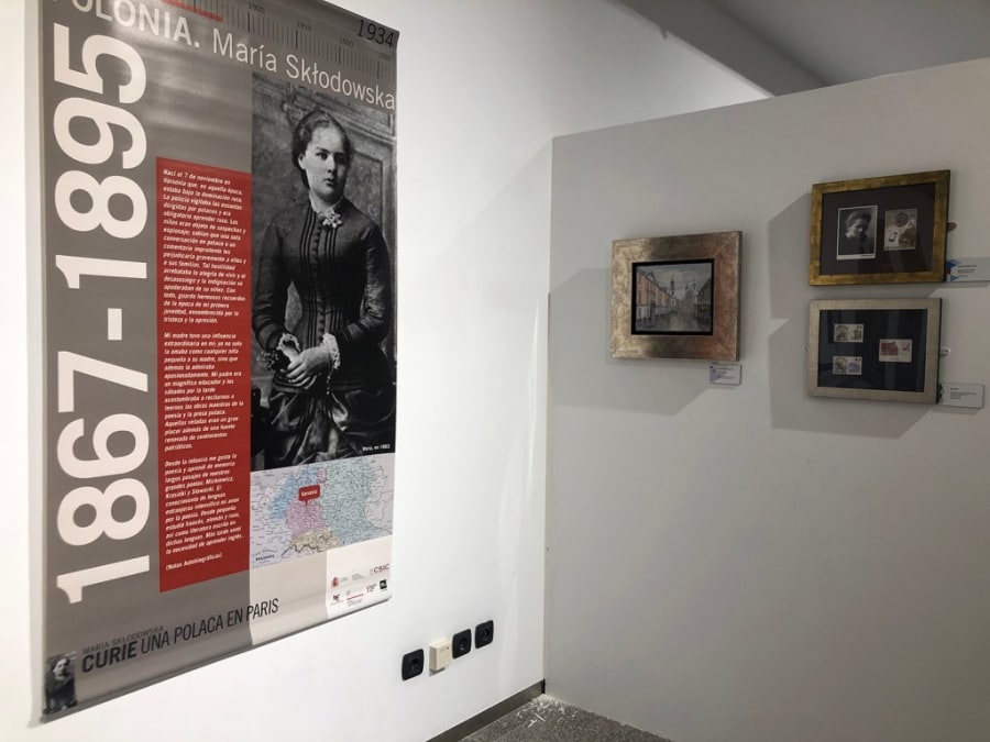 Panel de exposición sobre María Sklodowska-Curie, mostrando su biografía y logros científicos, acompañado de fotografías y objetos de la muestra.
