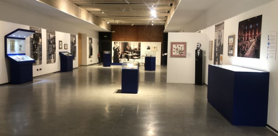Sala de exposición con paneles y vitrinas dedicados a María Sklodowska-Curie, mostrando documentos, objetos y fotografías sobre su vida y trayectoria científica.