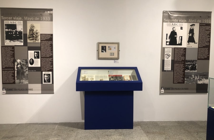 Exposición sobre María Sklodowska-Curie con paneles informativos y vitrinas mostrando documentos, fotografías y objetos relacionados con sus viajes a España en 1931 y 1933.