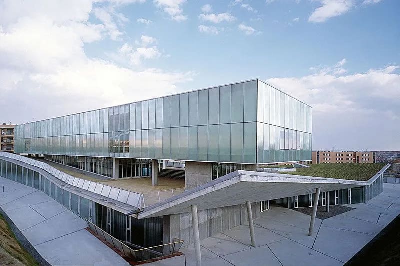 Vista moderna del Instituto de Neurociencias de Castilla y León, con su distintiva arquitectura de vidrio y concreto, rodeado por un paisaje abierto.