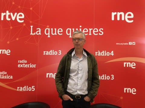 Hombre de pie frente a un fondo rojo con el logo de RTVE y el texto 