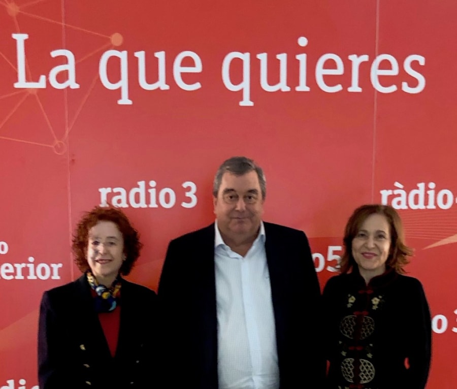 Tres personas posando en un evento en la estación de radio, con un fondo que lleva el texto 