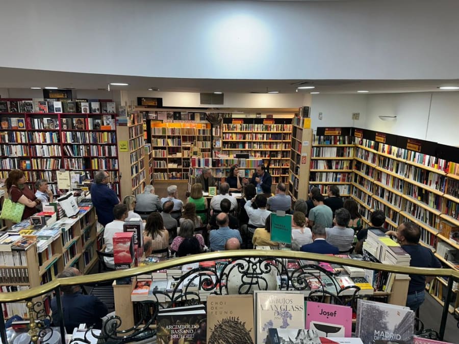 Vista general de una librería durante un evento literario, con un público concentrado escuchando a los ponentes en un espacio rodeado de estanterías llenas de libros.