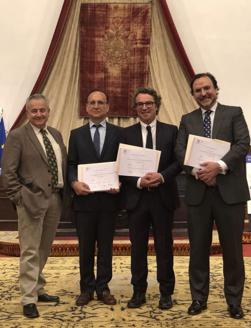 Ceremonia de entrega de diplomas en reconocimiento al archivo de Santiago Ramón y Cajal y la Escuela Española de Neurohistología, con cuatro asistentes sosteniendo los diplomas frente a una decoración de fondo.