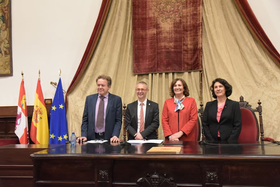 Ceremonia de entrega de diplomas de reconocimiento por la inscripción del Legado Cajal en la Memoria del Mundo de la UNESCO, con cuatro personas posando en una mesa frente a una decoración de fondo que incluye banderas de España y de la Unión Europea.