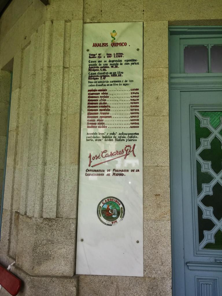 Placa de mármol que presenta un análisis químico del agua del manantial de Cabreiroá, con detalles sobre la composición del agua y la firma de José Casariego, catedrático de Farmacia.