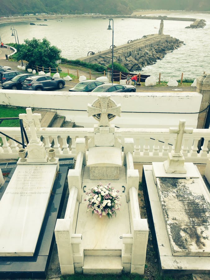 Tumba de Severo Ochoa en el cementerio de Luarca, decorada con flores, con vistas al mar Cantábrico.