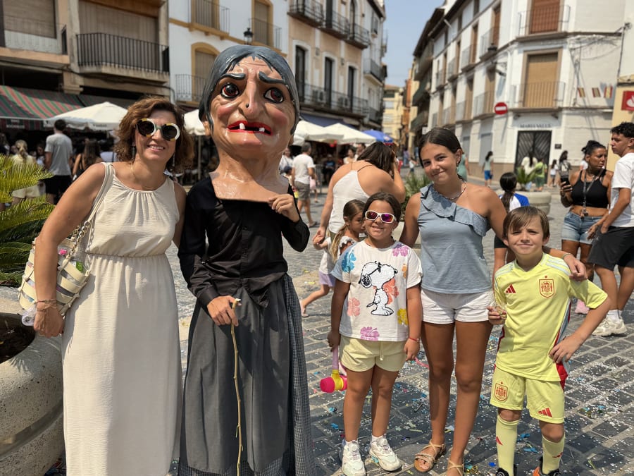 Grupo de personas posando con un cabezudo en una calle llena de gente, durante una festividad en España.