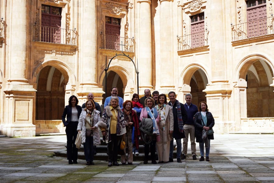 Grupo de personas posando en el patio de la Universidad Pontificia de Salamanca, rodeados de columnas y arcos arquitectónicos.