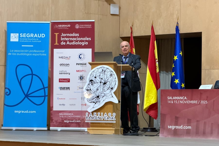 Ponente en la I Jornadas Internacionales de Audiología, Salamanca, 2025, frente a un atril con el logo de Santiago Ramón y Cajal y banderas de España y la UE.