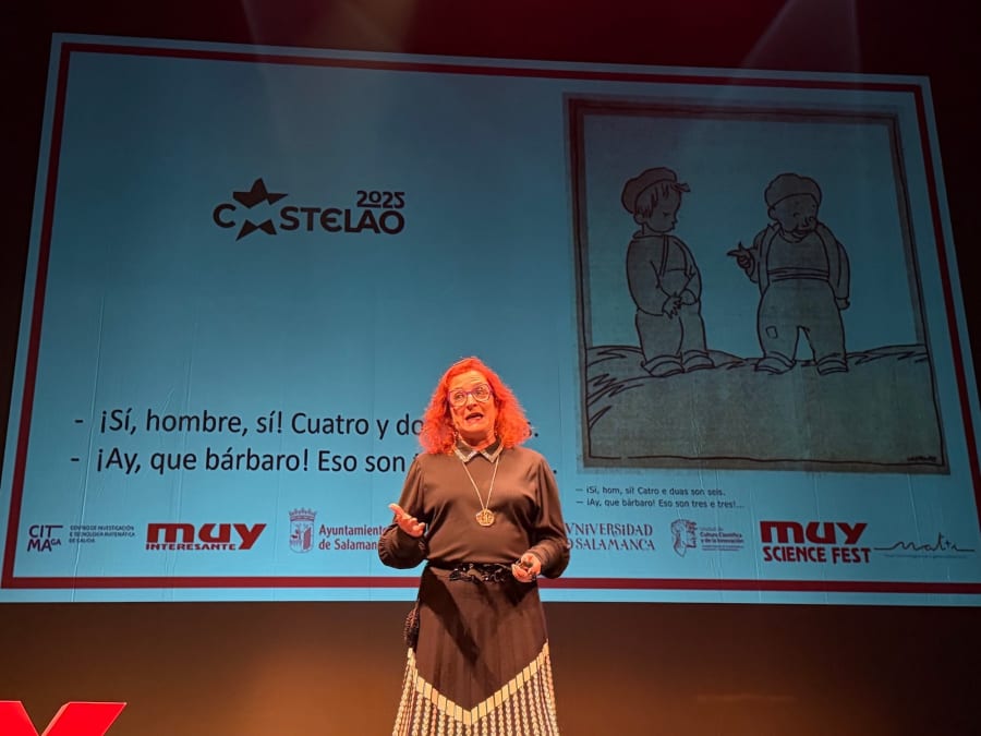 Oradora en el MUY Science Fest 2025 en el Teatro Liceo de Salamanca, mostrando una ilustración en la pantalla detrás de ella, mientras discute sobre un tema científico con humor.