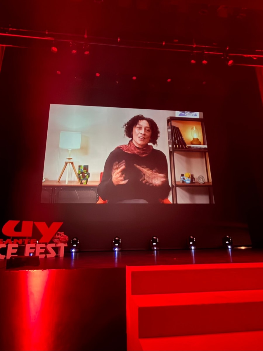 Presentadora en video durante MUY Science Fest 2025, con decoración moderna al fondo, hablando sobre ciencia y comunicación.