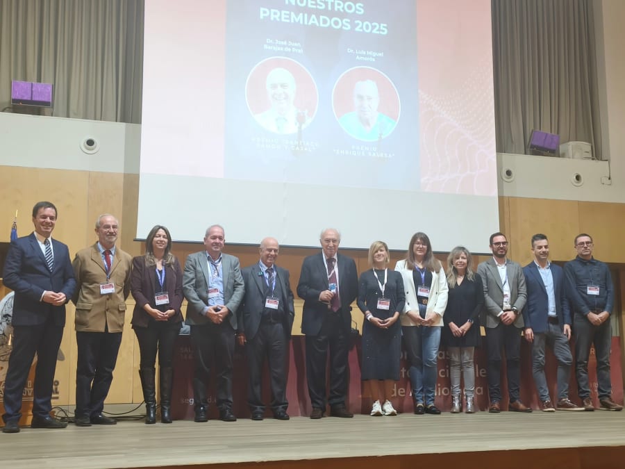 Grupo de personas en un escenario durante un congreso de audiología en Salamanca, con premiados y organizadores en primer plano.
