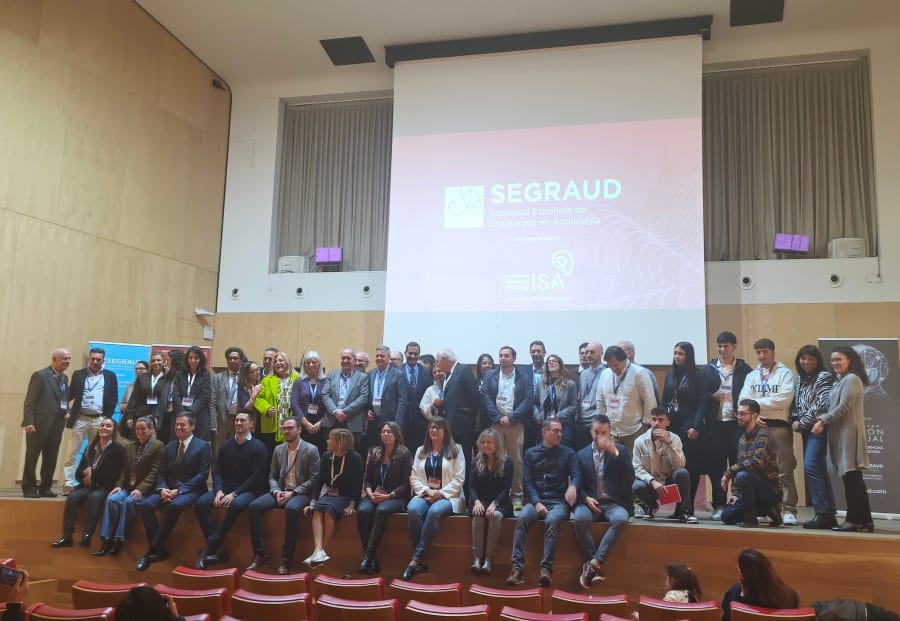 Grupo de participantes en las I Jornadas Internacionales de Audiología en Salamanca, posando en el escenario con el logo de SEGRAUD al fondo.