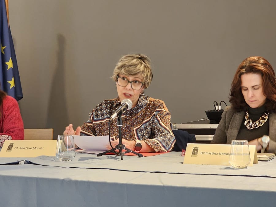 Dra. Ana Coto Montes, Catedrática de Biología Celular, hablando en un evento, con presentación en mesa.