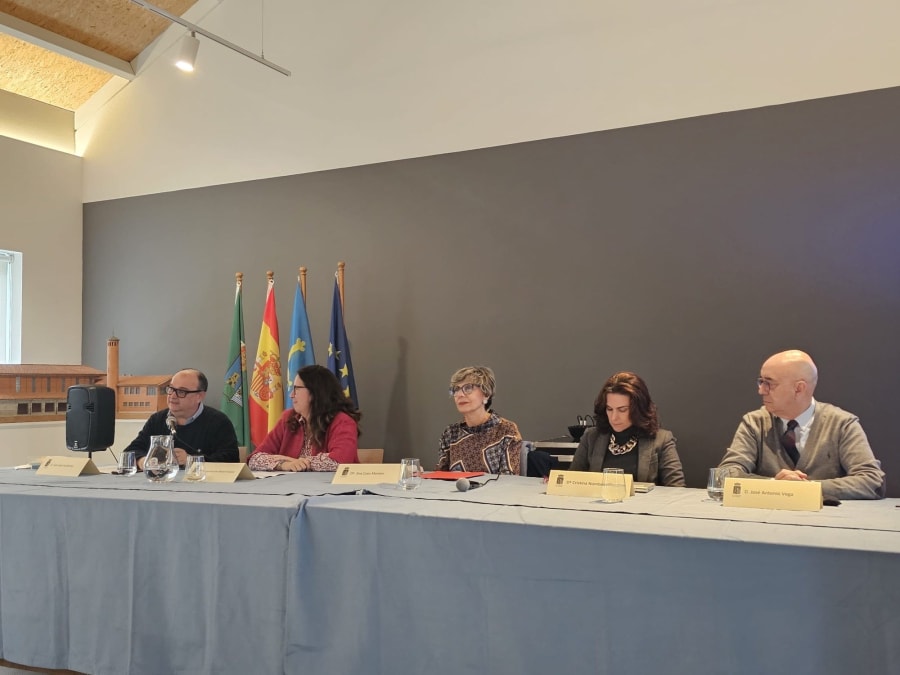 Mesa redonda durante el evento de homenaje a Santiago Ramón y Cajal en el Museo de la Mina de Arnao, con varios ponentes y banderas de España y Asturias en el fondo.