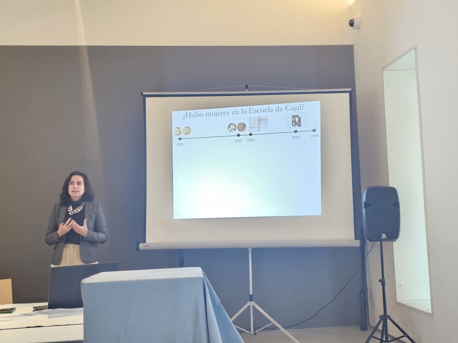 Conferencia sobre el papel de las mujeres en la escuela de Cajal, presentada por una mujer en un ambiente académico.