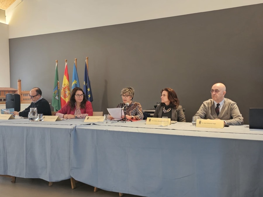 Mesa de conferencias en el Museo de la Mina de Arnao con cinco ponentes, acompañados por banderas de España y la Unión Europea.