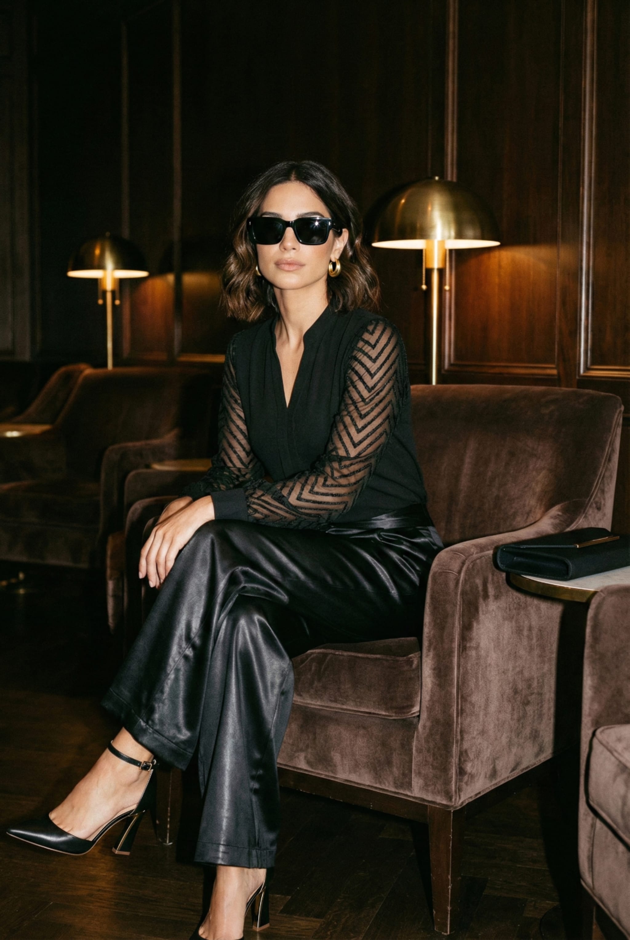 Close up of sheer paneled black blouse and gold hoop earrings next to an outfit flatlay. Left