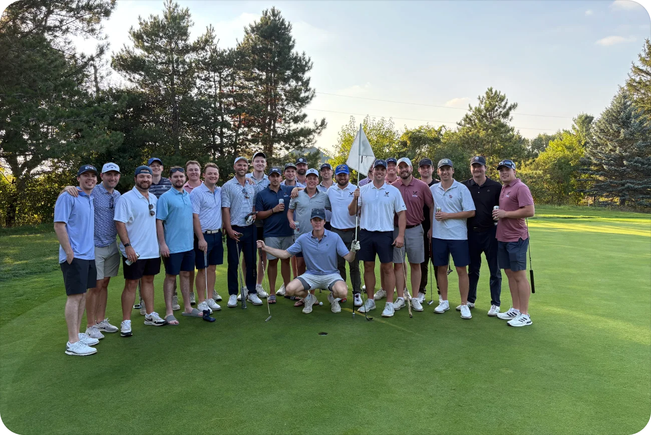 Large group of young men posing together on a golf course green