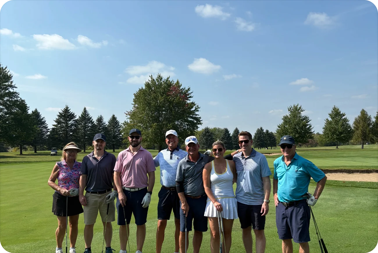 Group of eight golfers posing together on a sunny course