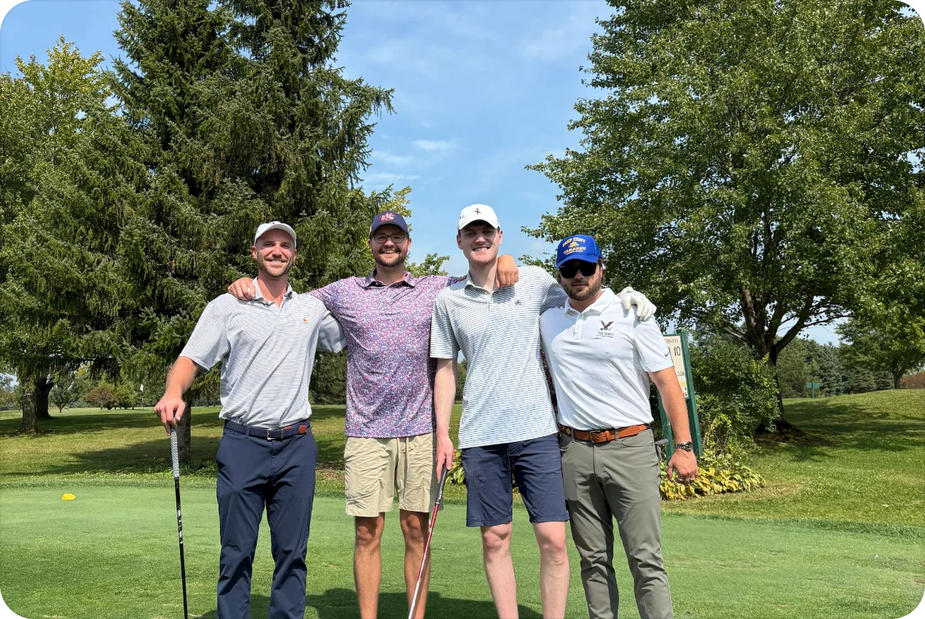 Four men smiling together on a sunny golf course