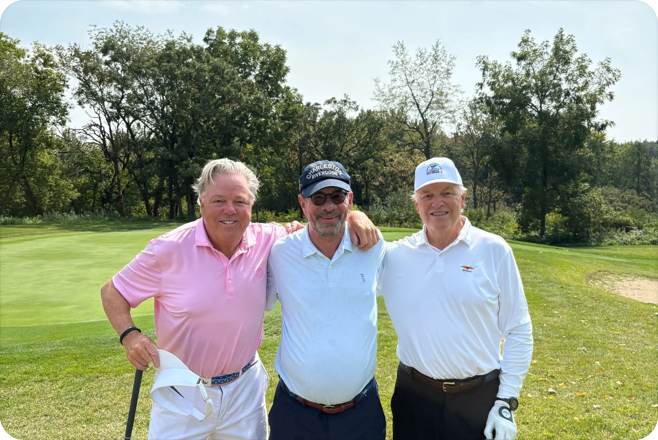 Three men smiling together on a sunny golf course