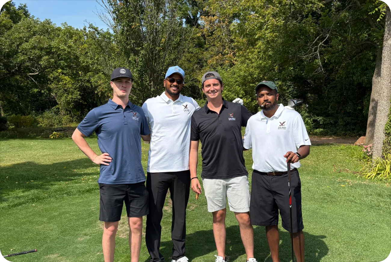Four men posing on a wooded golf course fairway