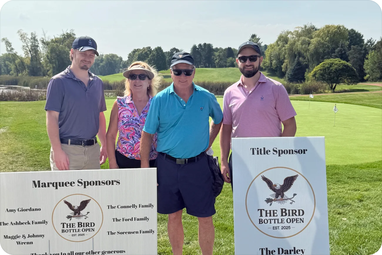 Four golfers posing next to Marquee Sponsors and Title Sponsor signs
